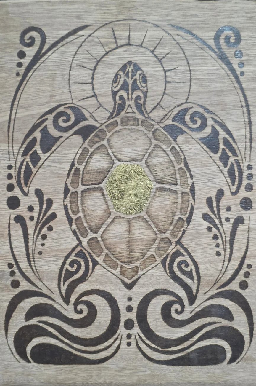 Sea turtle wood-burning artwork on oak with patterned flippers, gold leaf at the shell's center, a sunlike circle, and flowing decorative forms.