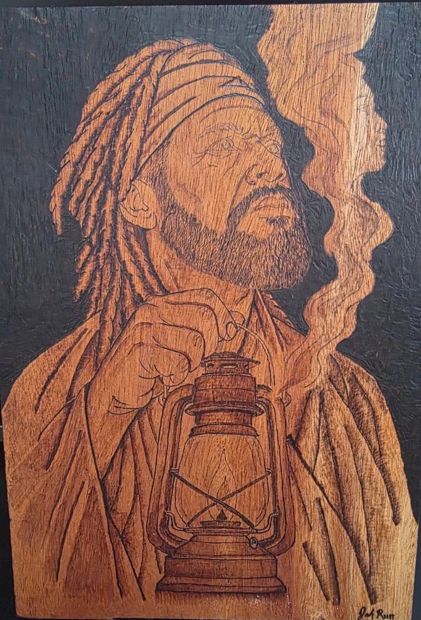 Wood-burned portrait on mahogany of a bearded man in a head wrap holding a lantern and looking upward, with smoke rising beside him against a dark burned background.